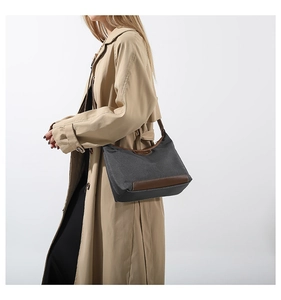 Detail showing dark grey nylon fabric handbag with premium brown leather trim and handle