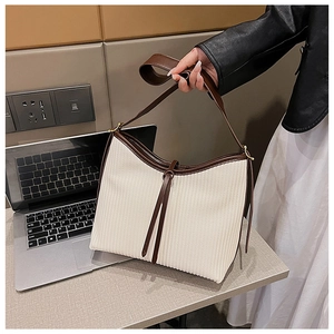 Detail of a vintage-style tote bag featuring off-white striped fabric and brown leather trim