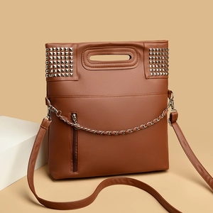 Brown leather handbag with silver stud details and metal chain on a beige background
