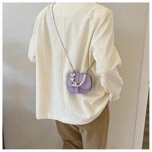 Détail du sac de selle violet avec pendentifs cœur argentés et chaîne en perles
