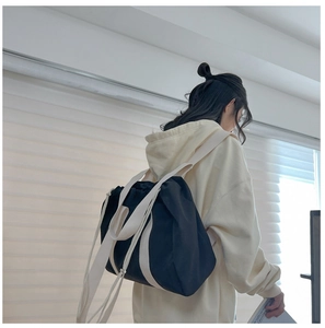Detail of black drawstring backpack with cream woven straps shown on shoulder