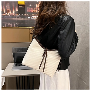Detail of hobo shoulder bag with pleated fabric and brown leather trim on a model