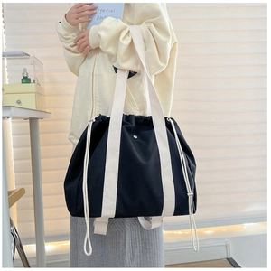 Detail of minimalist black canvas tote bag with contrast white strap and drawstring closure