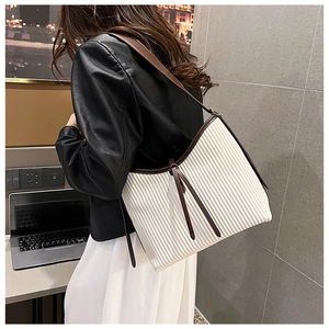 Detail of white pleated shoulder bag with dark brown straps and fringe tassels
