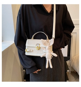 Détail d'un sac bandoulière en similicuir blanc grainé avec un porte-clé lapin en peluche