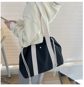 Close-up of black and white canvas tote bag with adjustable straps and drawstring detail