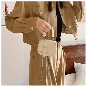 Détail du sac selle beige grainé avec poignée en perles et bandoulière chaîne