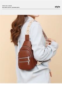 Detail of brown litchi leather crossbody bag with three zippers and patterned strap