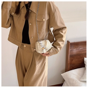 Vue détaillée du mini sac bandoulière crème avec breloque cœur et chaîne de perles