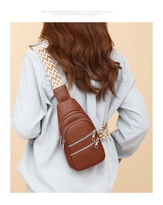 Detail of brown litchi pattern chest bag featuring three zip pockets and wavy strap