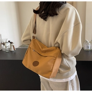Detailed back view of a yellow nylon crossbody bag shown in a minimalist cafe setting