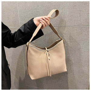 Detail view of beige pleated shoulder bag with delicate strap ties and gold hardware