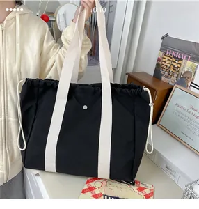 Close-up of black canvas tote bag featuring off-white wide straps and drawstring closure