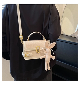Détail du sac blanc à motif litchi avec fermoir doré et breloque lapin mignonne