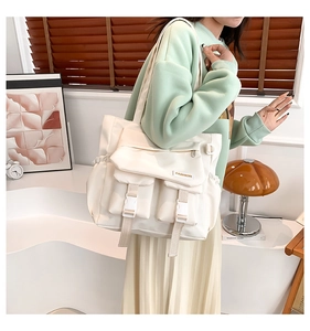 Détail d'un sac cabas blanc en nylon avec poches avant à boucles et étiquette mode