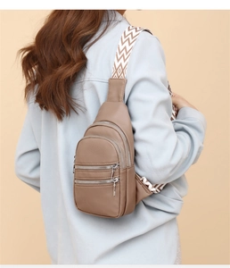 Detail of light brown PU leather crossbody bag with three zippers and woven zigzag strap