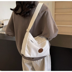 Detail of minimalist beige crossbody bag featuring side view and wide shoulder strap