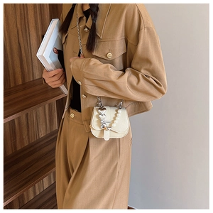 Détail d'un mini sac bandoulière blanc crème avec poignée perles et breloque coeur