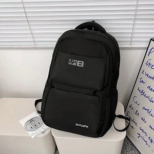 Minimalist black nylon backpack with multi-layered zippers and reinforced top handle