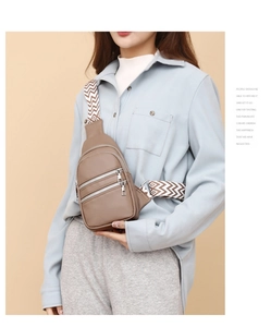 Close-up of khaki PU leather crossbody bag with wide chevron patterned strap and zippers