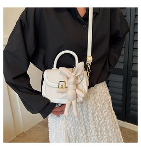 Close-up of white lychee pattern leather shoulder bag with gold square lock and rabbit charm