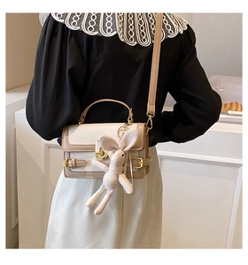 Détail du sac à bandoulière en similicuir crème avec pendentif lapin et fermoir doré chic