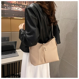 Detail of beige pleated shoulder bag with slim drawstrings and modern minimalist texture