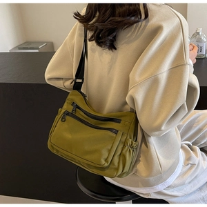 Detailed side view of green nylon crossbody bag showing storage pockets and wide strap