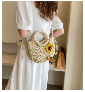 Detailed texture of straw shoulder bag with sunflower and pumpkin charms on a model