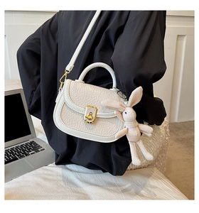 Detailed view of white lychee texture PU leather bag with cute rabbit charm and gold lock