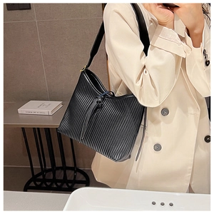 Detail of black pleated PU leather shoulder bag with wide strap and gold metal hardware