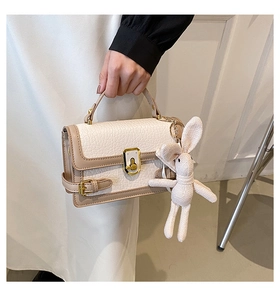 Détail d'un sac bandoulière crème et café avec fermoir doré et breloque lapin