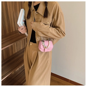 Détail du petit sac à bandoulière rose en PU avec chaîne cœur et perles porté par mannequin