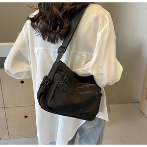Detail showing multi-pocket structure and durable nylon fabric of black crossbody bag