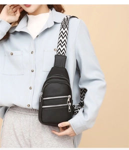 Close-up of black pebble leather crossbody bag with silver zippers and geometric strap