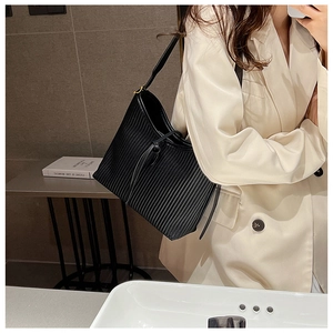Detail view of black vertical pleated shoulder bag showing unique matte faux leather texture