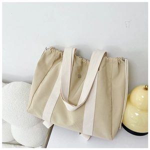 Minimalist beige canvas tote bag with drawstring closure and wide fabric handles