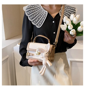Détail du grain de cuir litchi et du fermoir en métal doré sur le sac bandoulière