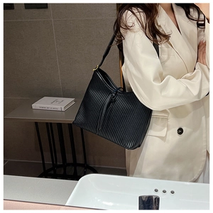 Close-up of black pleated tote bag with adjustable strap and golden metallic hardware