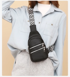 Detail of black pebbled leather crossbody bag with ethnic wide strap and silver zippers
