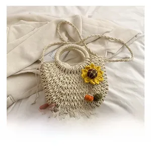 Detail of straw shoulder bag with sunflower ornament and woven handles on soft fabric