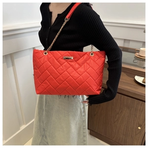 Detail der knallroten PU-Handtasche mit goldener Kette und eleganter Chevron-Steppung im Fokus