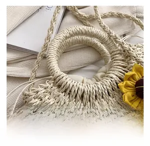 Dettaglio della borsa in paglia intrecciata con fiore giallo e fodera a coulisse