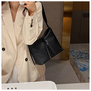 Detail of black pleated tote bag with vertical accordion texture and slim drawstrings