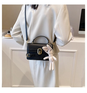 Détail du sac à bandoulière noir effet crocodile avec fermoir doré et breloque lapin