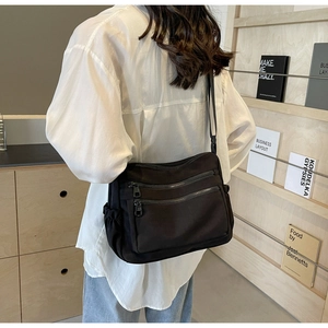 Detail view of large black nylon crossbody bag with multiple zippers and side pocket