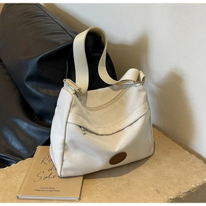Minimalist beige canvas crossbody bag with multi-pocket design on a stone platform