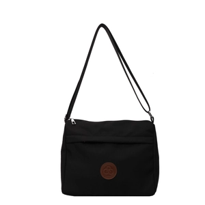 Minimalist black fabric crossbody bag with adjustable strap and leather logo patch
