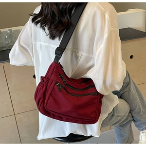 Detail showing red nylon crossbody bag with gold zippers and adjustable shoulder strap