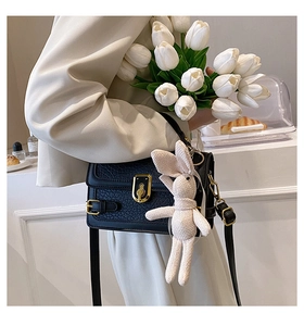 Détail d'un sac en cuir PU vintage noir avec fermoir doré et accessoire de lapin en tricot